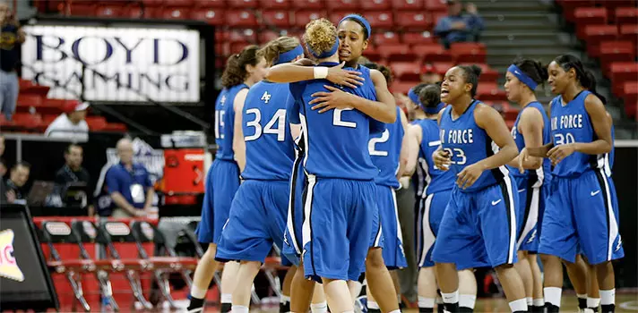 Women's basketball team in blue Air Force uniforms celebrating and embracing after game
