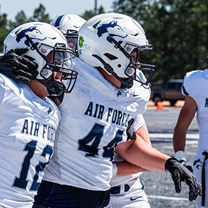 Football players in white Air Force jerseys with falcon helmets during practice