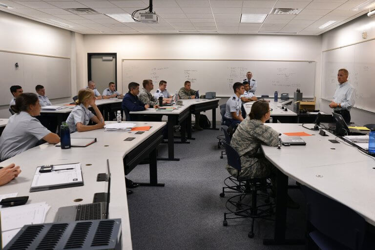 Air Force officers in uniforms attend graduate lecture in modern classroom with whiteboards