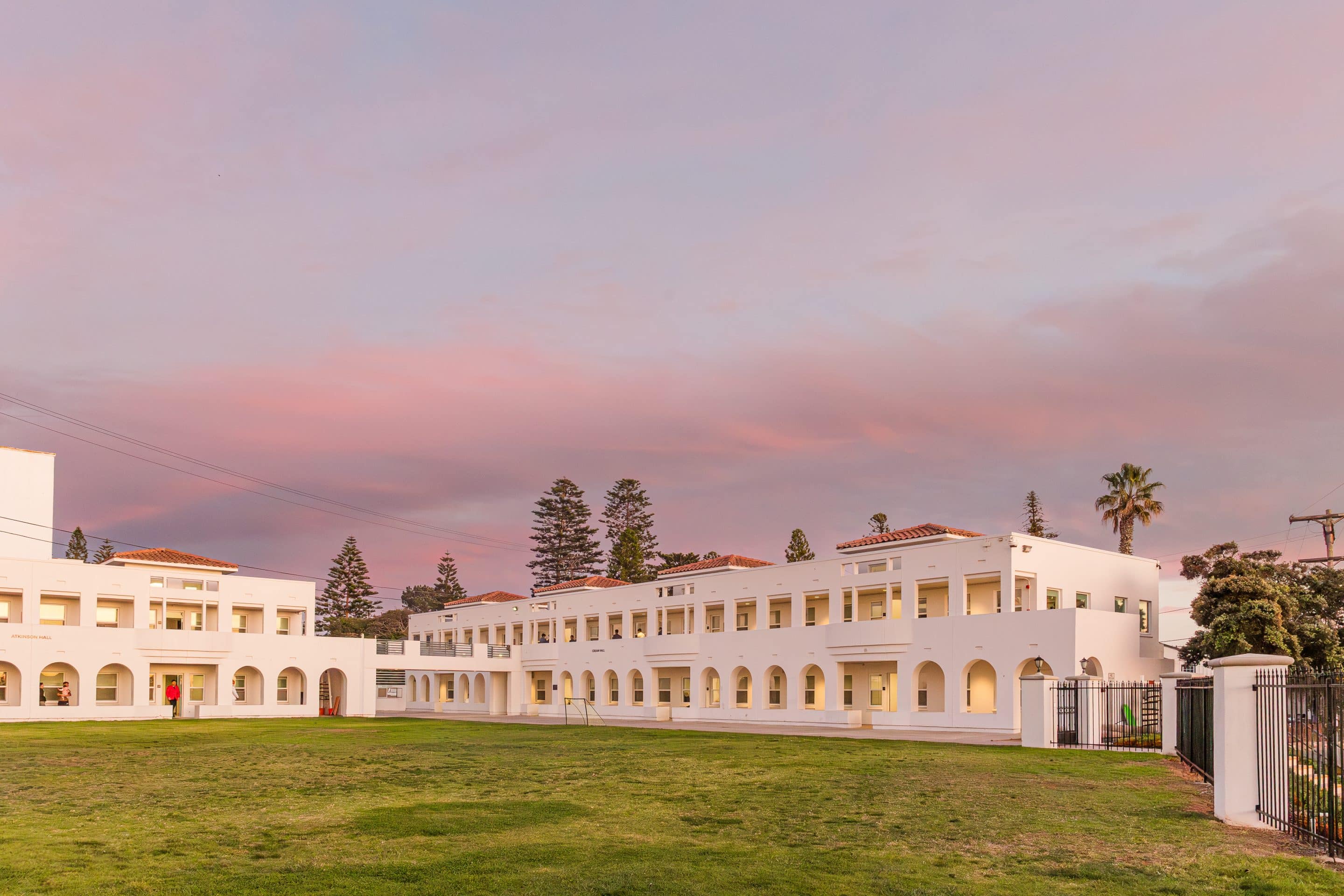 White Spanish colonial barracks building with arched walkways at sunset with pink and blue sky
