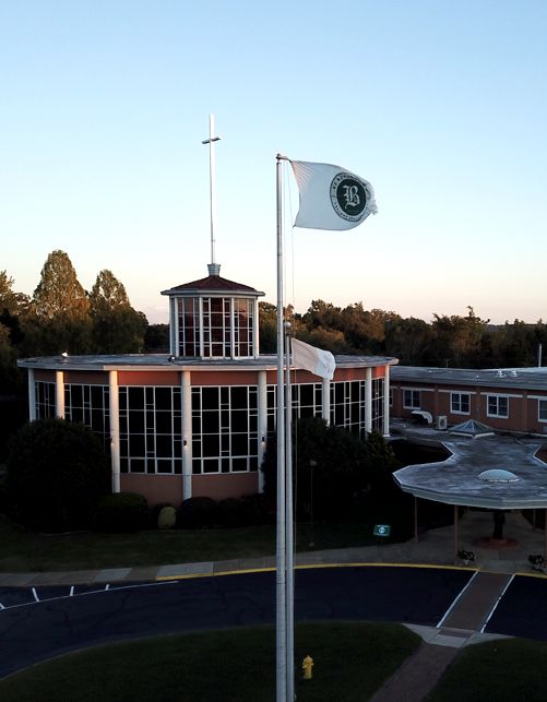 Benedictine campus at dusk featuring circular tower building with large windows and school flag flying