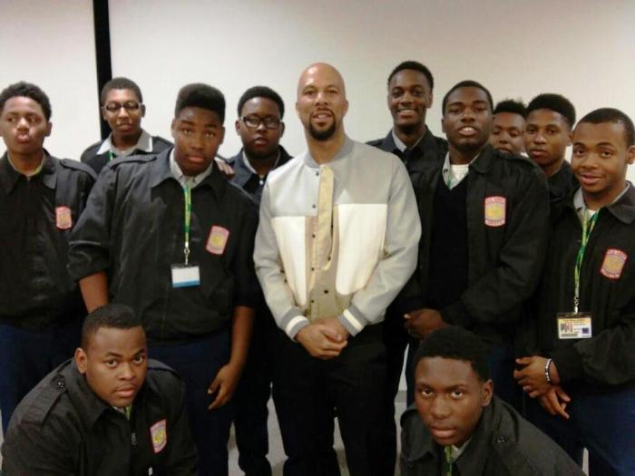 Cadets in dark JROTC uniforms with school patches posing with guest speaker