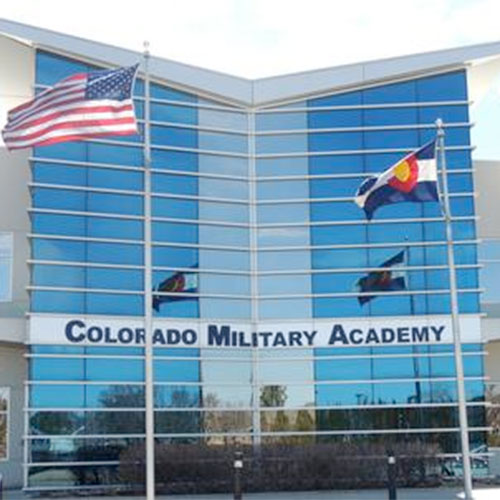 Modern blue glass Colorado Military Academy building with American and Colorado state flags