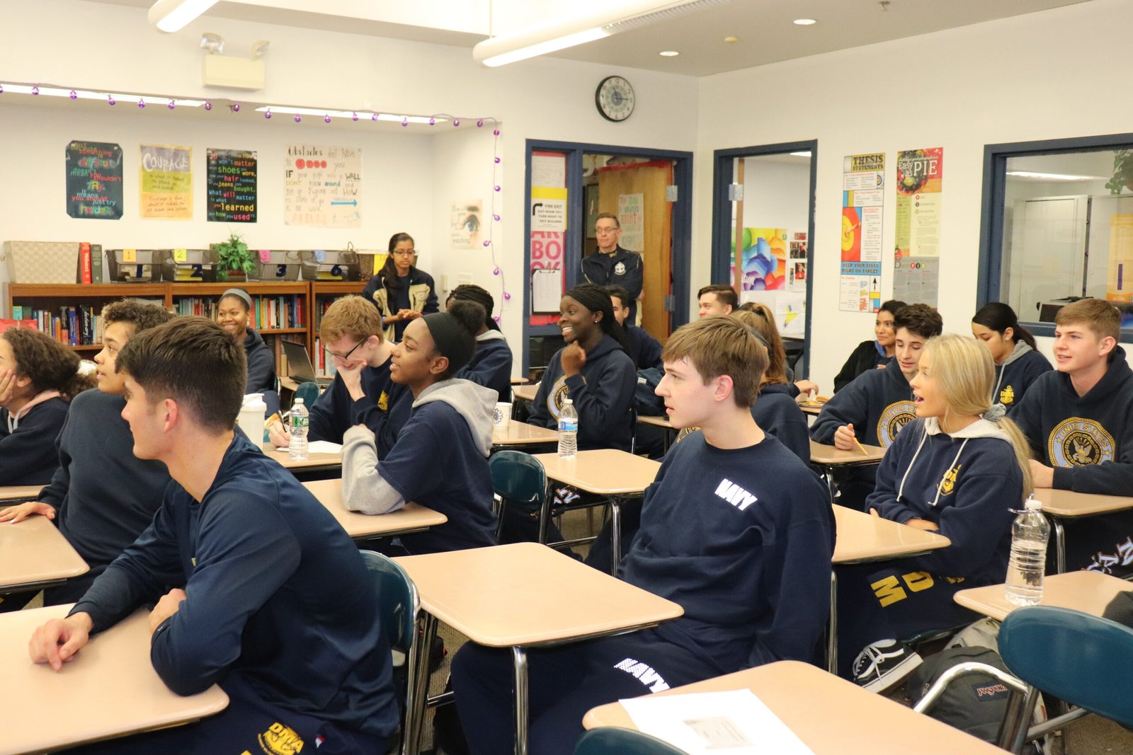 Cadets in navy blue NJROTC uniforms seated at desks during classroom instruction