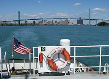 View from training ship deck with orange life ring, American flag, suspension bridge, and city skyline