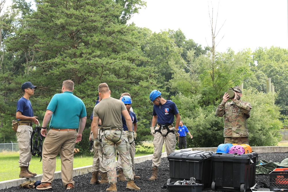 Cadets preparing for rappelling training with blue helmets and harnesses alongside National Guard instructors