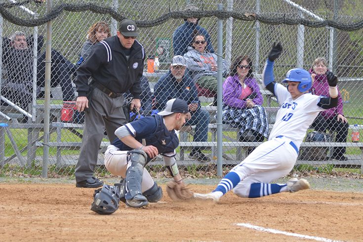 Baseball player in blue and white Cadets uniform sliding into home plate during game