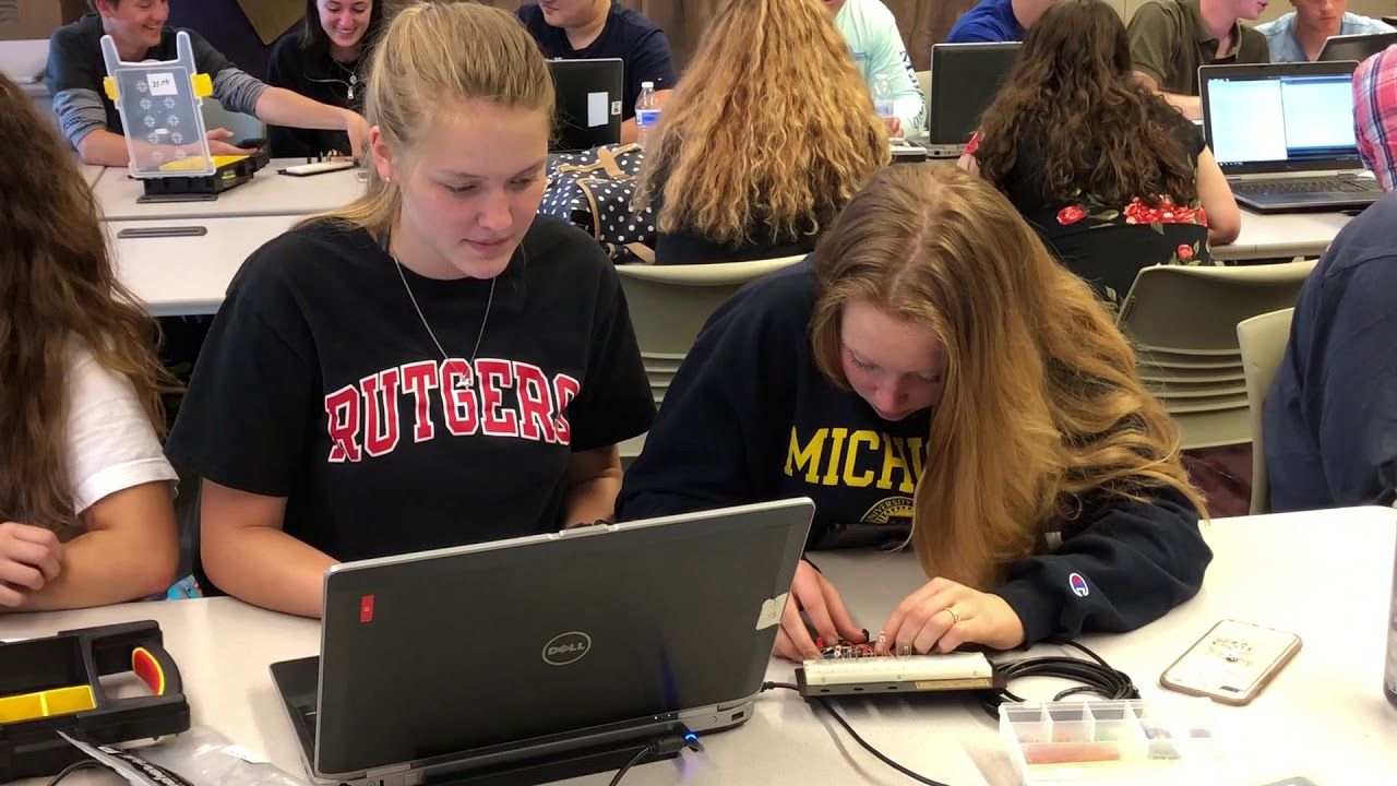 Students in college sweatshirts working on electronics and circuits with laptops in classroom lab