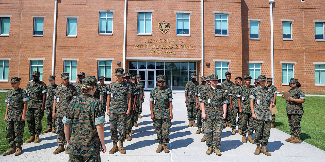 Cadets in Marine woodland camo uniforms at formation in front of red brick main building