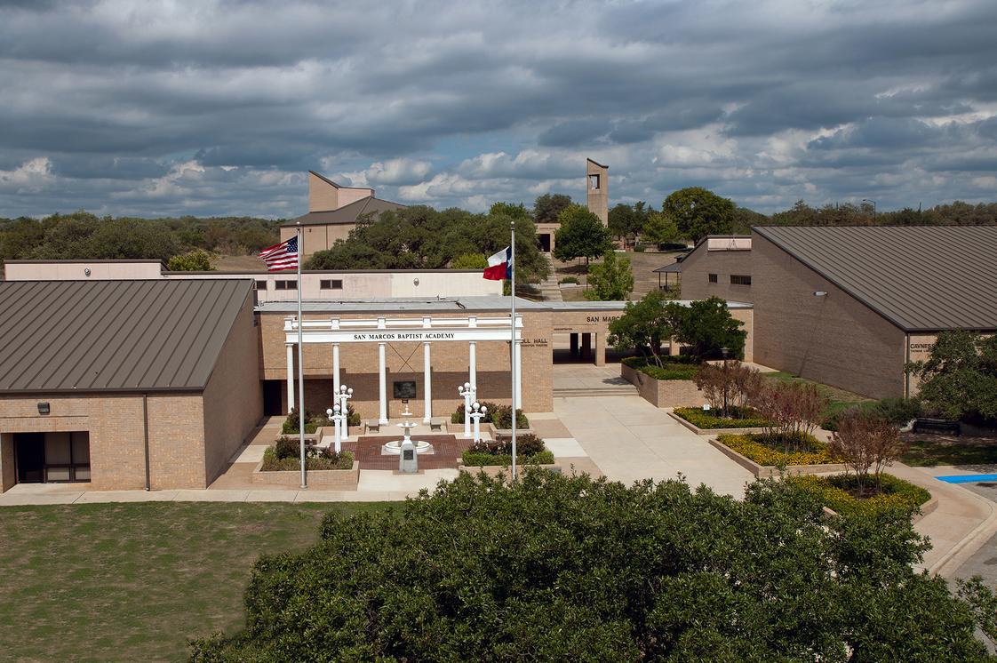 Aerial view of campus buildings with central quad, bell tower, and Texas Hill Country backdrop