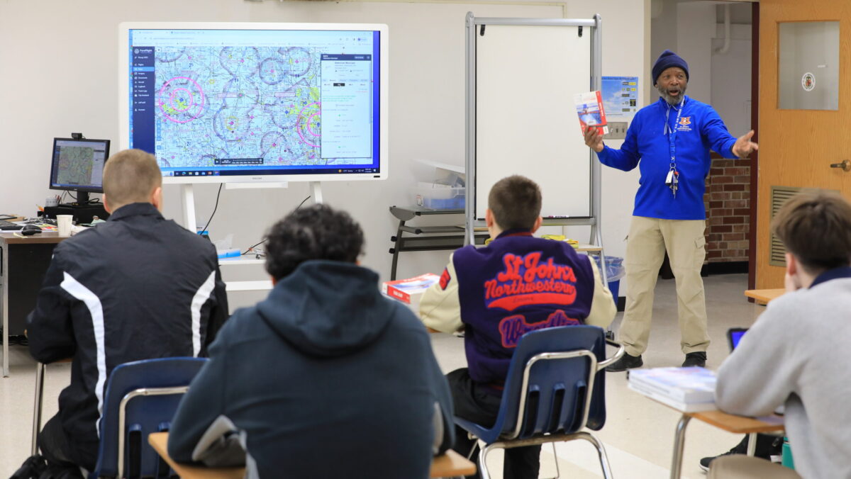 Aviation instructor teaching flight navigation with aeronautical charts on digital display to students