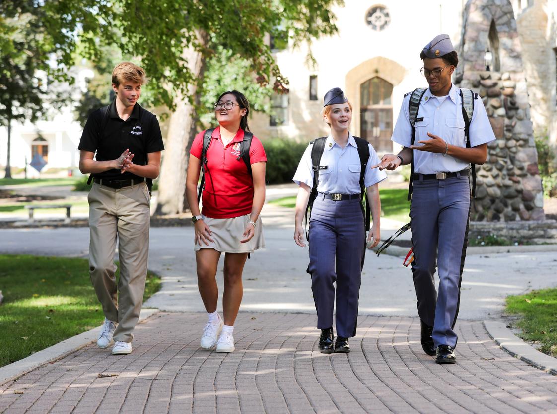 Four students walking on brick pathway - two in military uniforms, two in Leadership Academy polo attire
