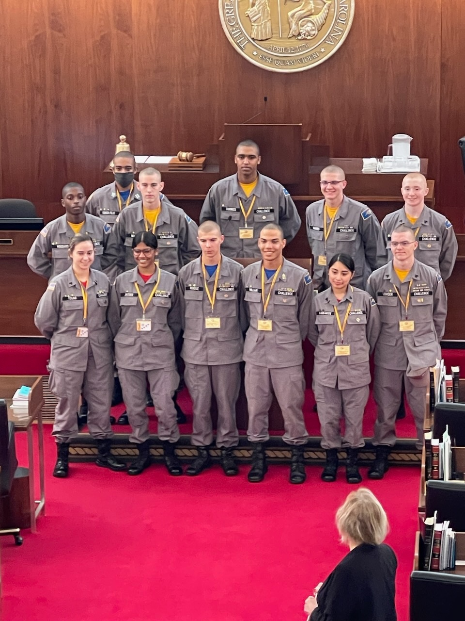 Cadets in gray uniforms posing in North Carolina courtroom beneath state seal