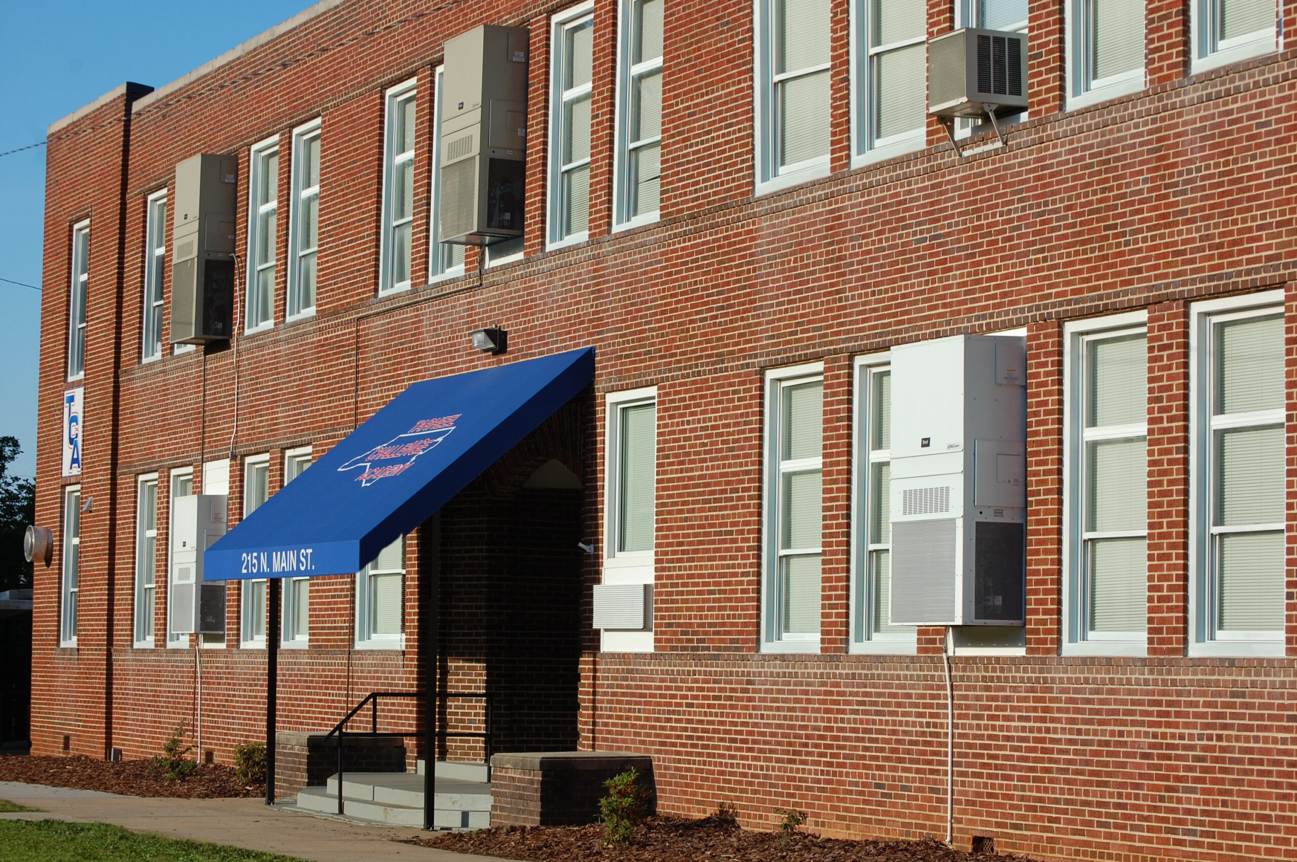 Three-story red brick building with blue awning entrance at 215 N Main St