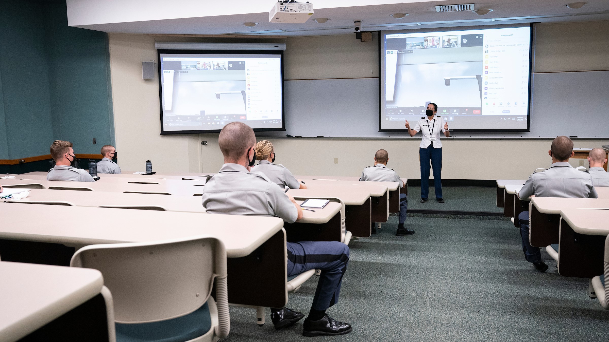 Instructor in uniform teaching cadets in modern classroom with dual projection screens