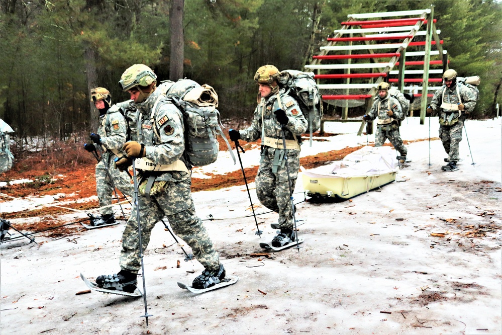 Cadets in winter gear snowshoeing with backpacks through snowy forest during field training