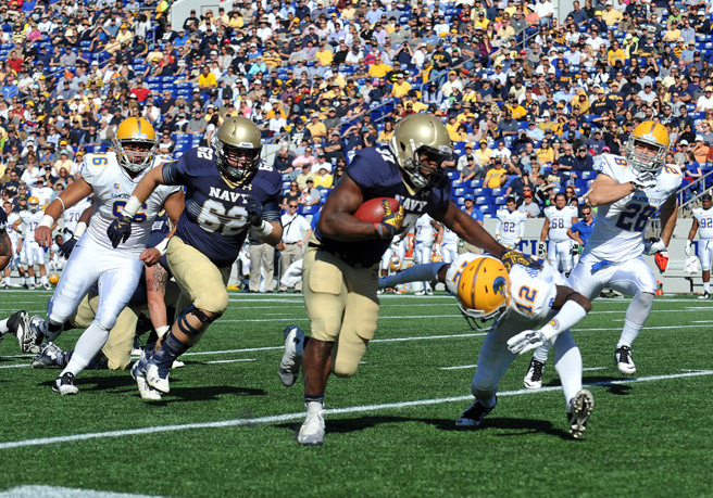 Navy football running back in navy and gold uniform evading defenders during game action
