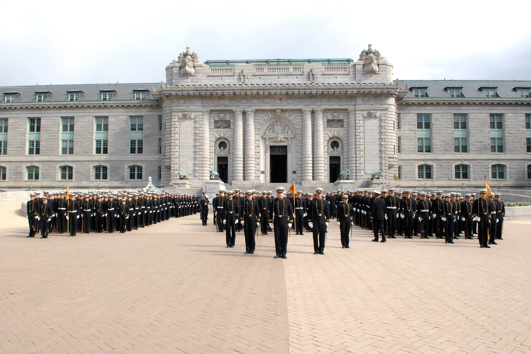 Brigade of Midshipmen in dress blues standing in formation on Tecumseh Court in front of Bancroft Hall